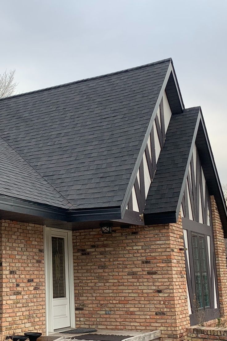 Dark architectural shingle roof with crisp rake edges above a brick and timber facade