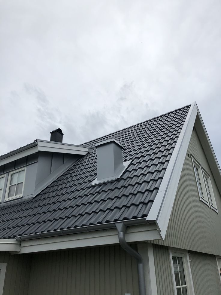 Charcoal metal tile roof with new chimney and skylight flashing on a gabled home