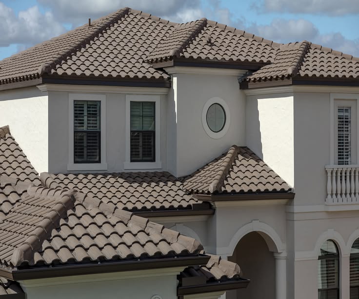 Barrel tile roof with dark drip edge on a large stucco estate home